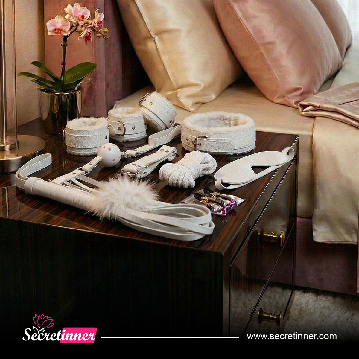 Collection of white leather restraints on a wooden surface with a bed and pillows in the background, featuring the Secretinner brand.