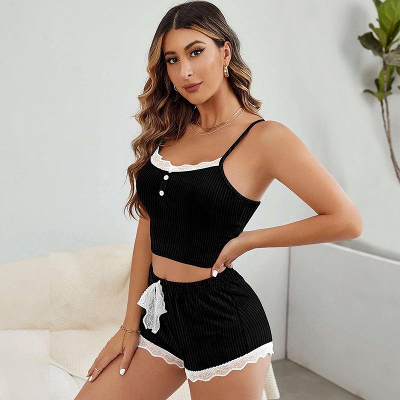 Woman wearing a black ribbed crop top and shorts with lace trim in a minimalistic room.