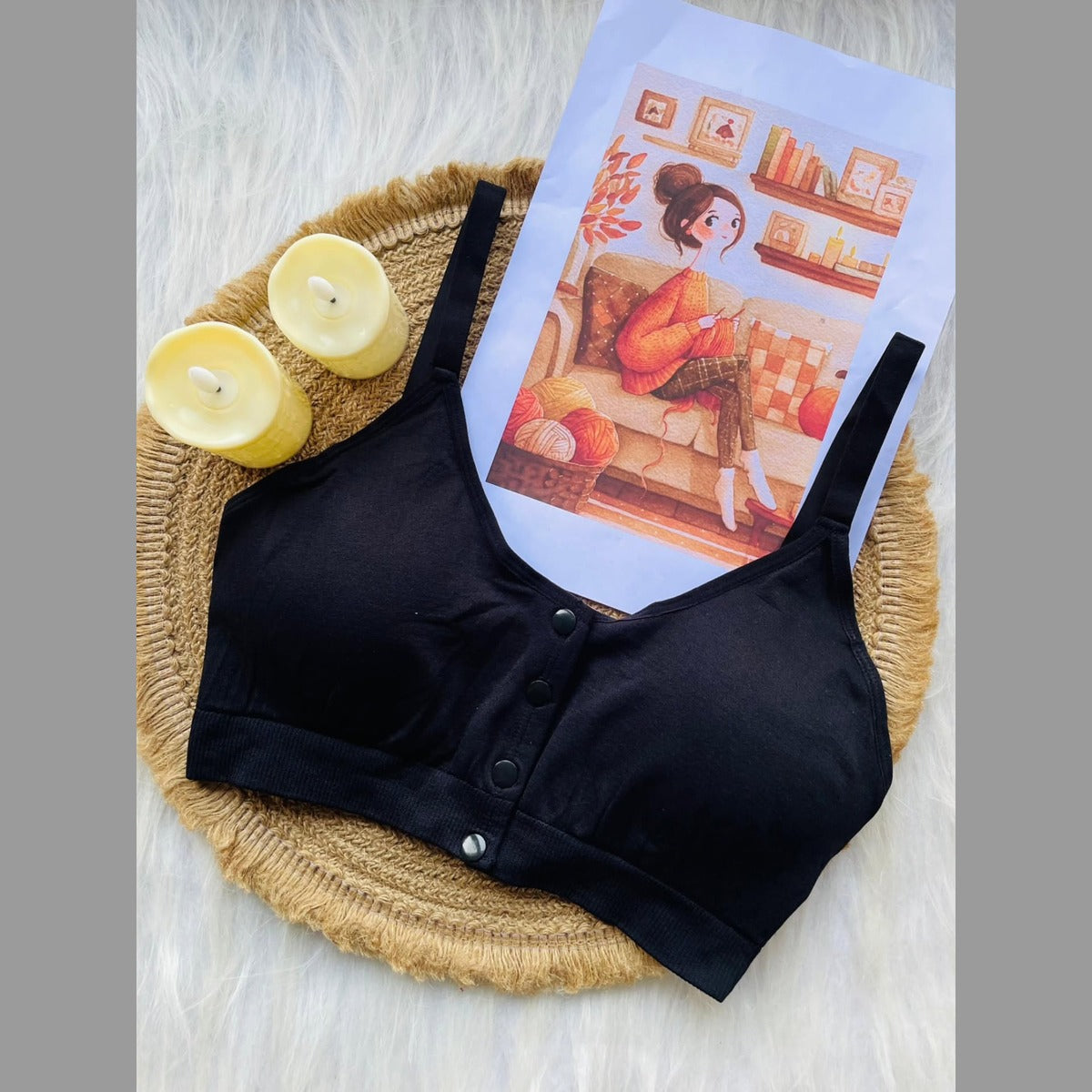 Black bralette on a woven tray with candles and a magazine featuring a woman on a couch.