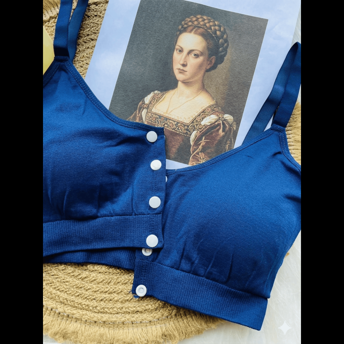 Blue bra with white buttons on a woven mat with a portrait in the background