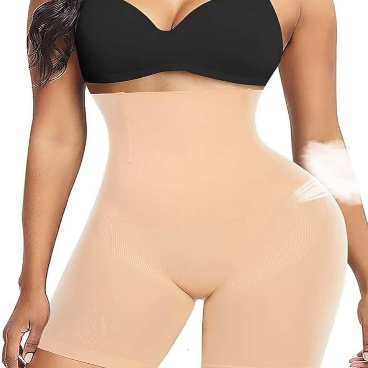 Woman wearing a black bra and beige shapewear on a white background