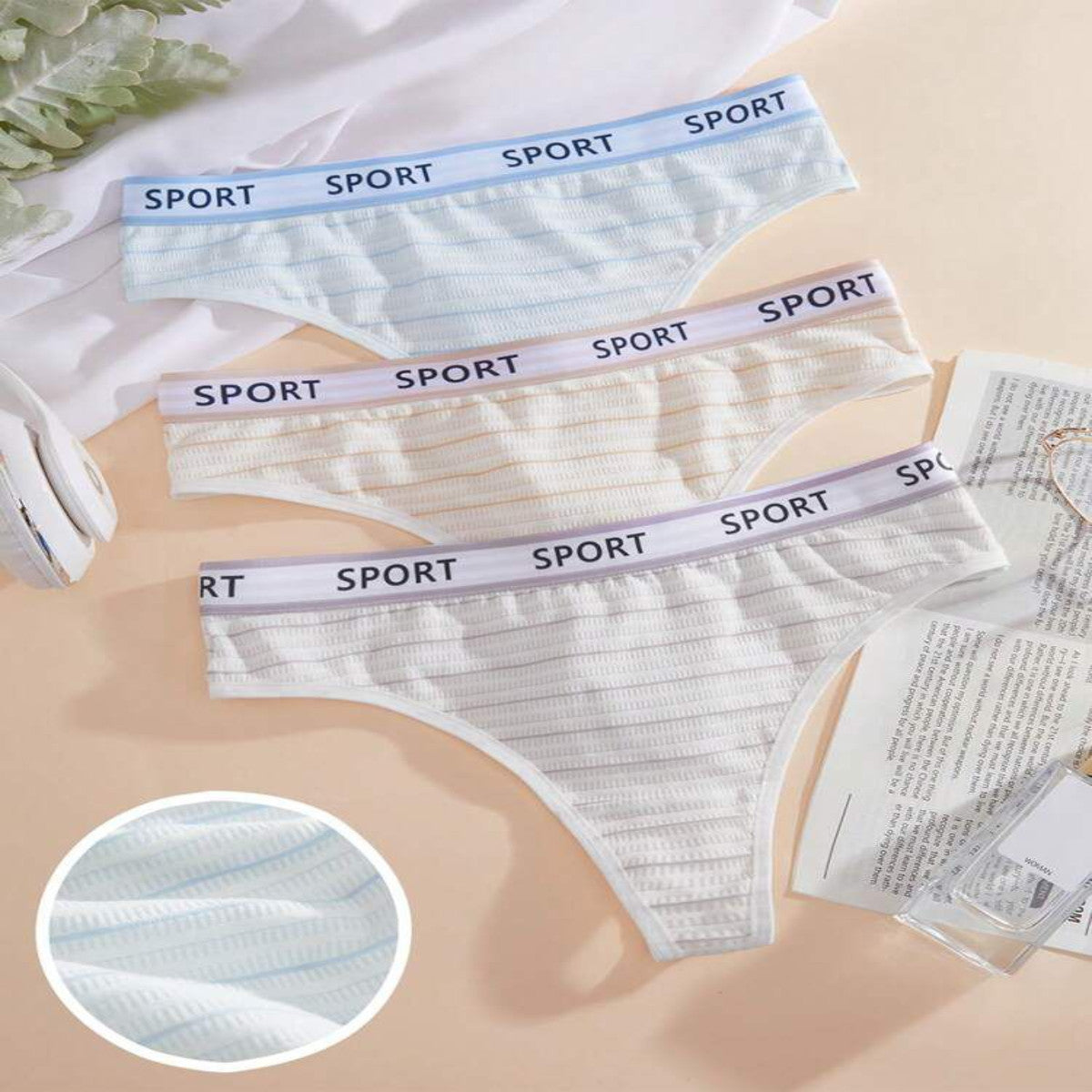 Set of light blue and white men's underwear with 'SPORT' label on a beige background.