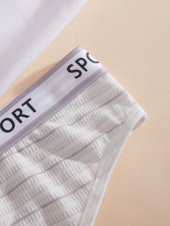 White athletic shorts with a gray waistband displaying the word 'SPORT' on a beige background
