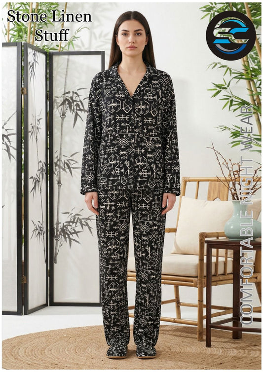 Woman wearing a black patterned pajama set in a home setting with decor elements.